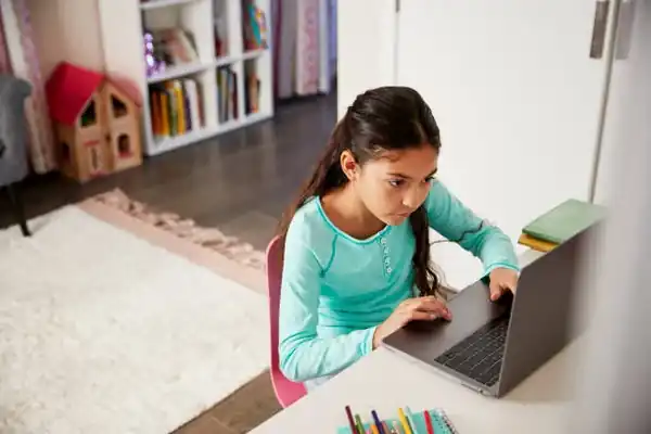 A young learner working through a lesson on a laptop at home