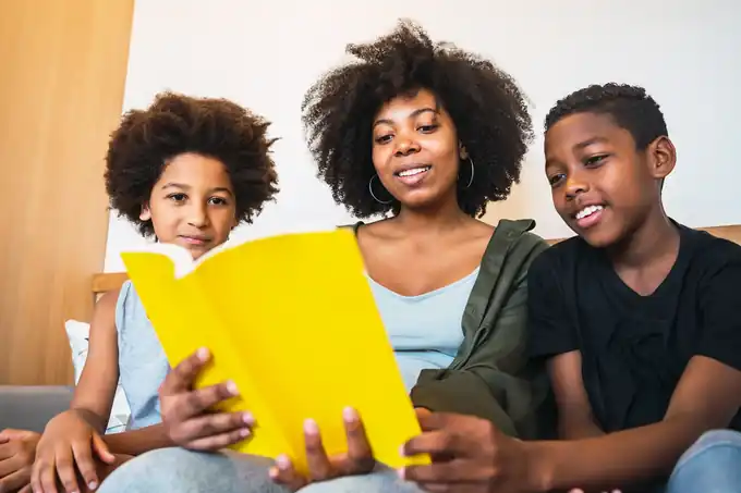 A mother reading a book with her two children at home